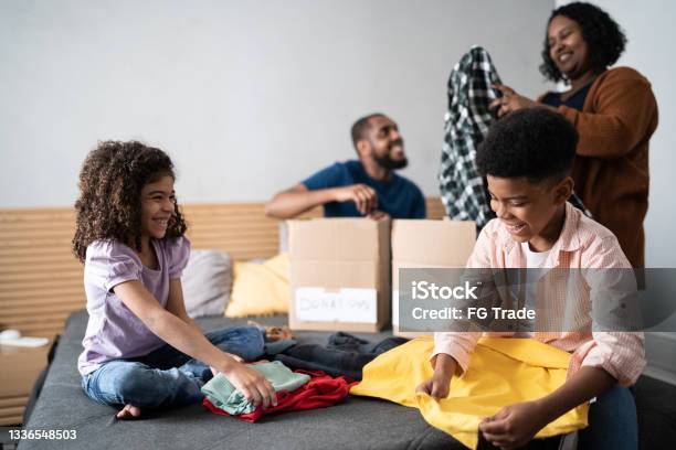 Parents with children sorting out clothes in boxes to donate at home