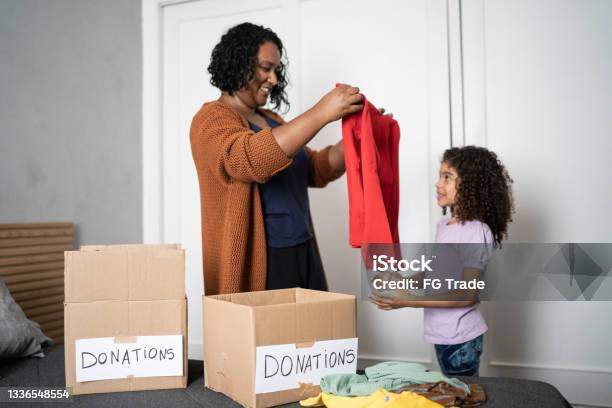 Mother And Daughter Sorting Out Clothes In Boxes To Donate At Home Stock Photo - Download Image Now