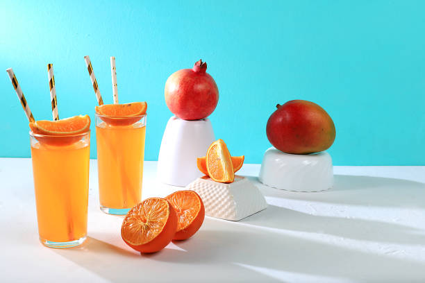 istock Modern still life with citrus, orange juice and ingredients on colored bright background with long hard shadows, minimal detox diet concept, 1336548828