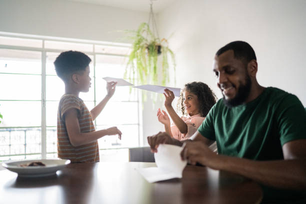 istock Father doing paper airplane and siblings playing with it at home 1336548940