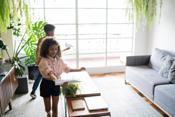 istock Siblings playing with paper airplane at home 1336548981