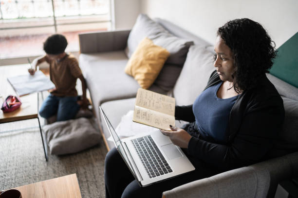 frau, die mit notizblock und laptop zu hause arbeitet oder studiert - to do list organization life family stock-fotos und bilder