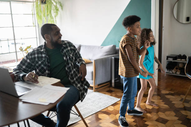 istock Father working while watching chilndren play at home 1336549549