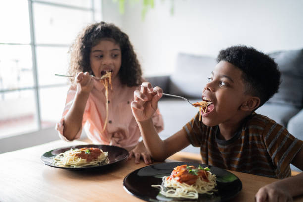 istock Siblings at table eating at home 1336549898