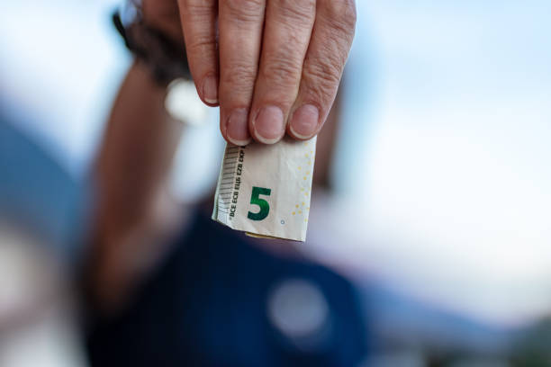 cinque euro piegati in una mano focalizzata in primo piano - focus on foreground tax close up finance foto e immagini stock