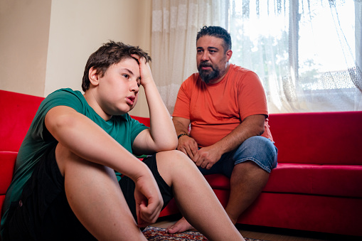 Upset teenage boy talking with his father.