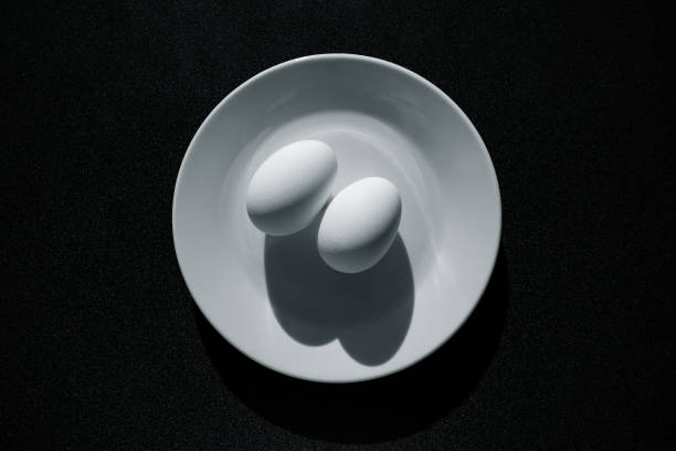 istock Breakfast - two chicken eggs on a plate with contrasting shadows, black and white image. 1336556518