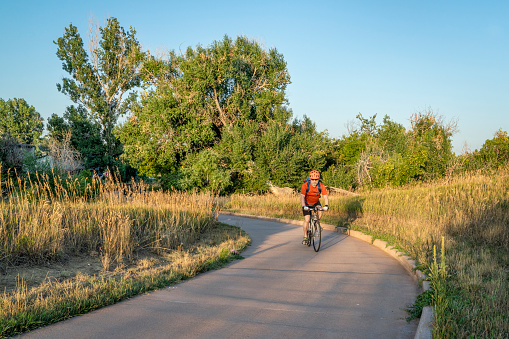 Senior male cyclist is commuting on a bike trail in Fort Collins in northern Colorado, late summer scenery