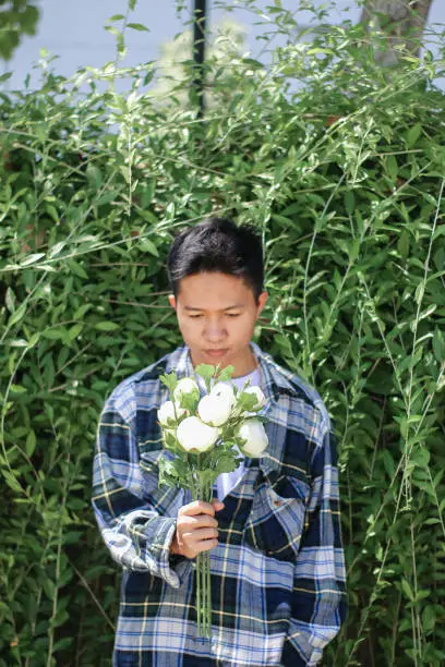 Photo of young men holding of white rose flowers at park garden