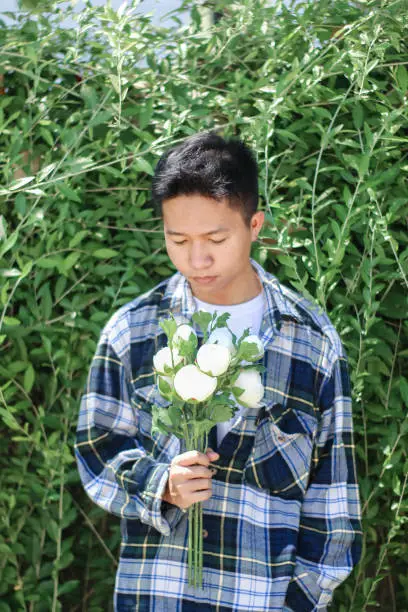 Photo of young men holding of white rose flowers at park garden