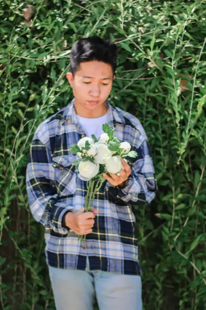 Photo of young men holding of white rose flowers at park garden