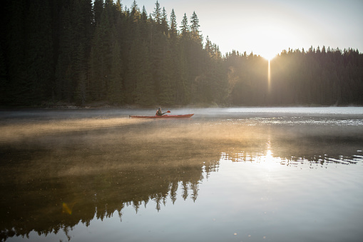 Kayaking in beautiful lake at sunrise.