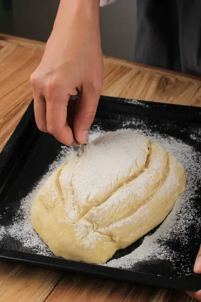 Baking Process: Making Bread, Scoring Raw Round Japanese Milk Hearth Bread Dough. Female Hand Making Cross Cut on the Top of Dough Using Razor