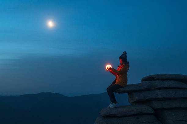 una ragazza era seduta su una pietra e teneva una lampada sotto la luna - ground asia night light foto e immagini stock