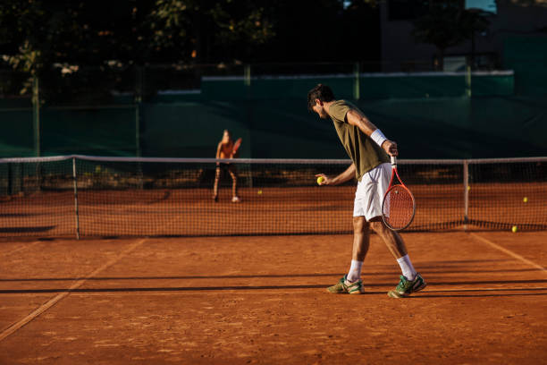 He does not go easy on her Fit young man playing tennis with his girlfriend on a clay court clay court stock pictures, royalty-free photos & images