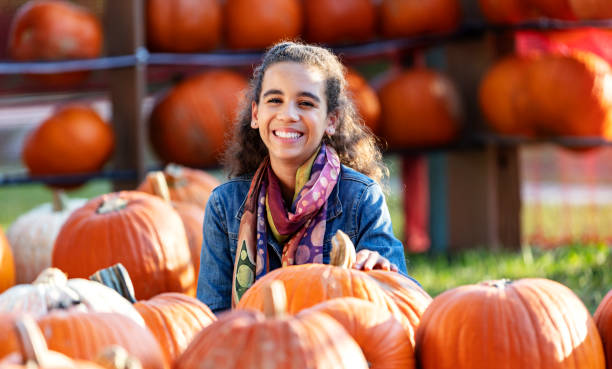 istock Girl sitting in pumpkin patch smiling at camera 1336579022