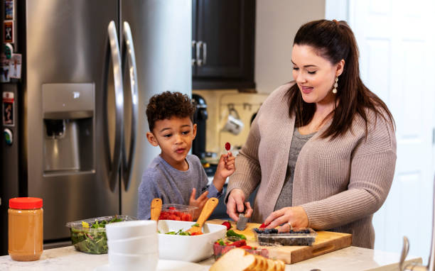 istock Mother in kitchen making salad, son watching 1336579024