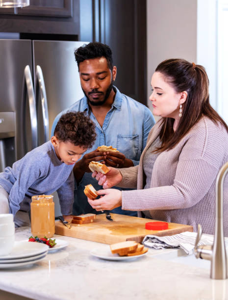 istock Multi-ethnic family make, eat peanut butter sandwiches 1336579600