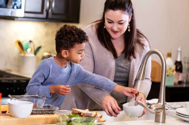 istock Boy with mother at kitchen sink, washing strawberry 1336579608