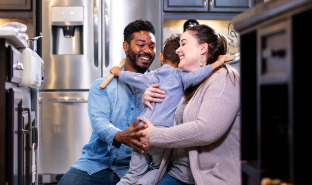 istock Multi-ethnic family in kitchen, boy hugging parents 1336579639
