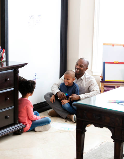 vater zu hause verbringt zeit mit seinen beiden kindern - child playroom parent indoors stock-fotos und bilder