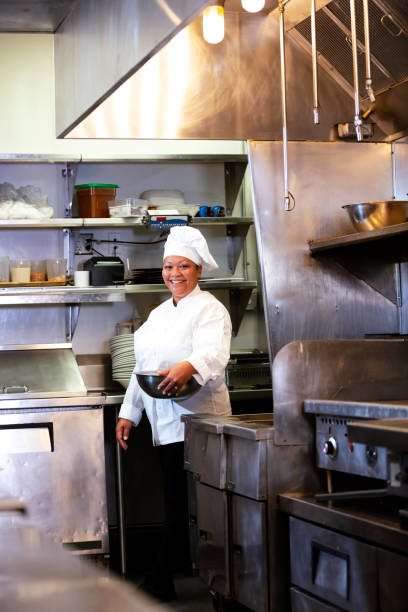 istock Female chef in commercial kitchen smiling, carrying bowl 1336580768