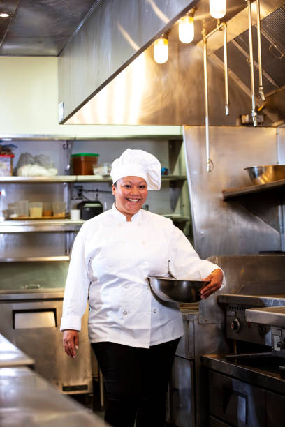 istock Female chef in commercial kitchen smiling, carrying bowl 1336580802