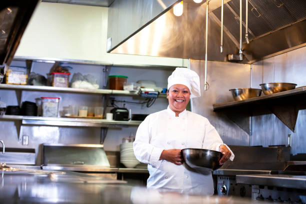 istock Female chef in commercial kitchen smiling, carrying bowl 1336580806