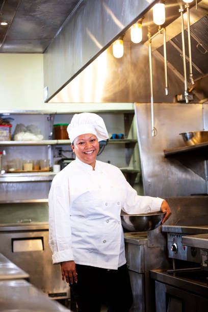 istock Female chef in commercial kitchen smiling, carrying bowl 1336580816