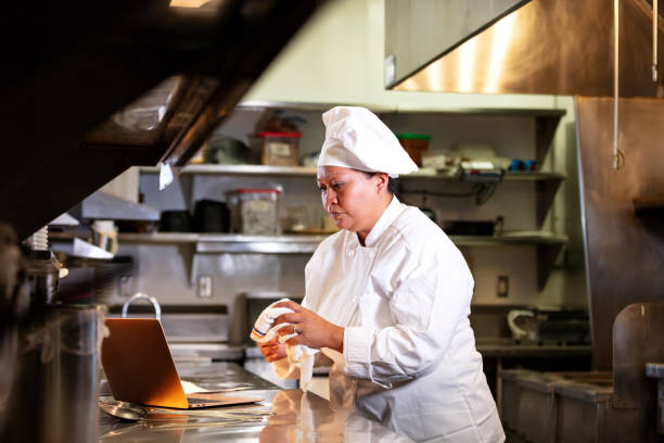 istock Female chef in commercial kitchen using laptop 1336582362