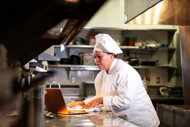 istock Female chef in commercial kitchen using laptop 1336582364