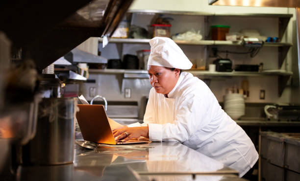 istock Female chef in commercial kitchen using laptop 1336582366