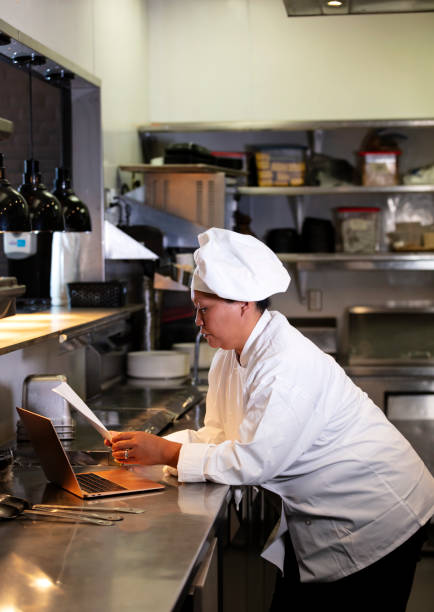 istock Female chef in commercial kitchen using laptop 1336582897