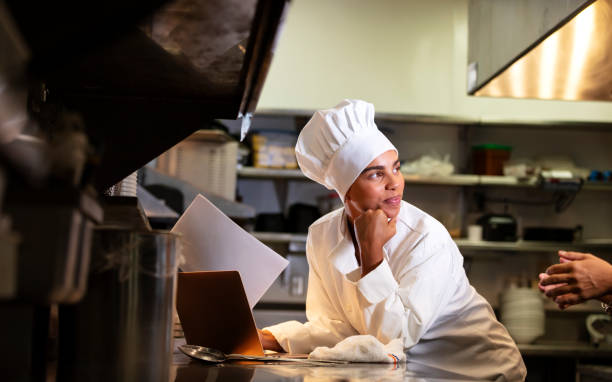 Female chef in commercial kitchen using laptop