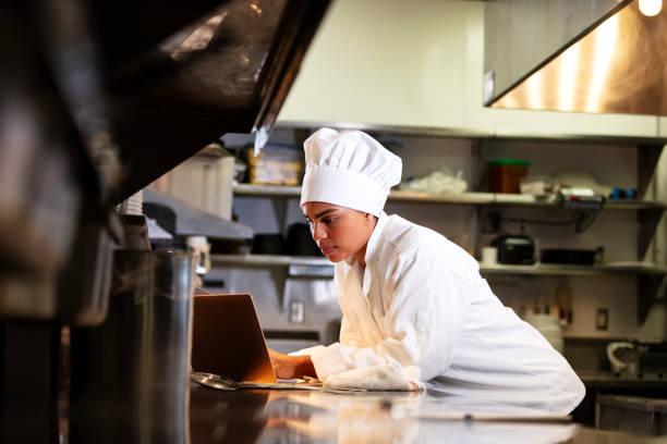 istock Female chef in commercial kitchen using laptop 1336583950