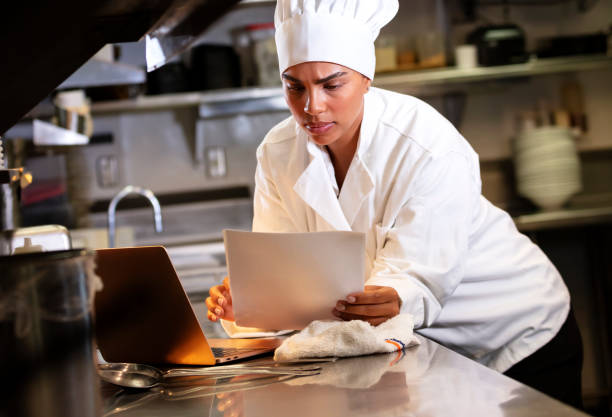 istock Female chef in commercial kitchen using laptop 1336583956