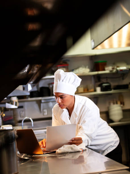 istock Female chef in commercial kitchen using laptop 1336584459