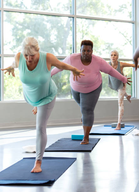 istock Three mature women taking yoga class, in warrior 3 pose 1336585524