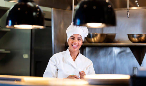 istock Female chef in restaurant kitchen behind serving counter 1336585529