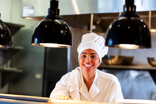 istock Female chef in restaurant kitchen behind serving counter 1336586034