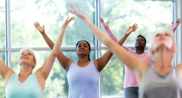 istock Four women taking yoga class, standing with arms raised 1336586040