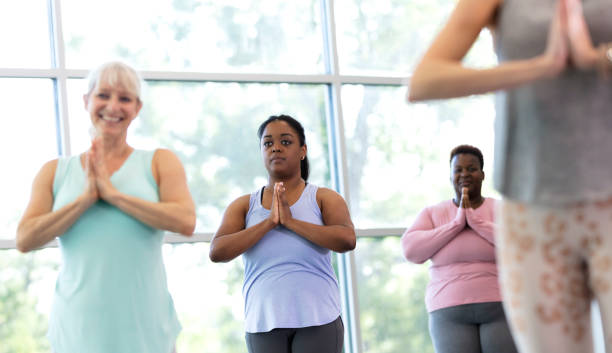 istock Four women taking yoga class, in tree pose, prayer hands 1336586546