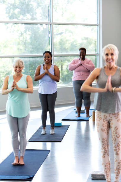 istock Four women taking yoga class, in tree pose, prayer hands 1336586559