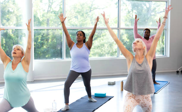 istock Four women taking yoga class, in warrior 1 pose 1336587075