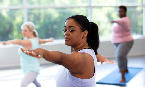 istock Three women taking yoga class, in warrior 2 pose 1336587596