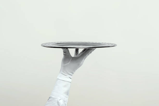 istock The waiter's hand in white gloves holds a silver tray. Isolate on a light background. 1336592367