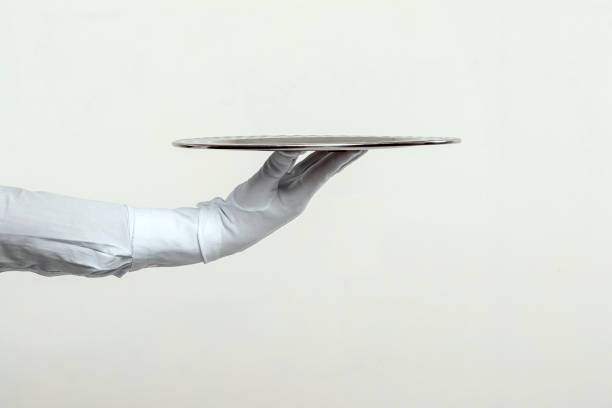 istock The waiter's hand in white gloves holds a silver tray. Isolate on a light background. 1336592368