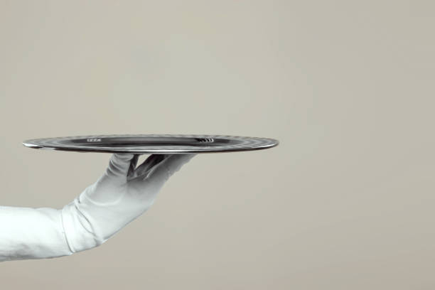 istock The waiter's hand in white gloves holds a silver tray. Isolate on a light background. 1336592370