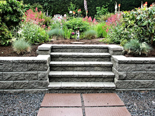 Staircase with Block Wall Block retaining wall with incorporated staircase into existing garden landscape consisting of perennial flowers and bushes with stepping stones leading up to the steps. hardscape photos stock pictures, royalty-free photos & images