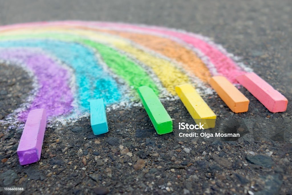 Chalk drawing rainbow colors on the asphalt, children outdoors. Chalk Drawing Stock Photo